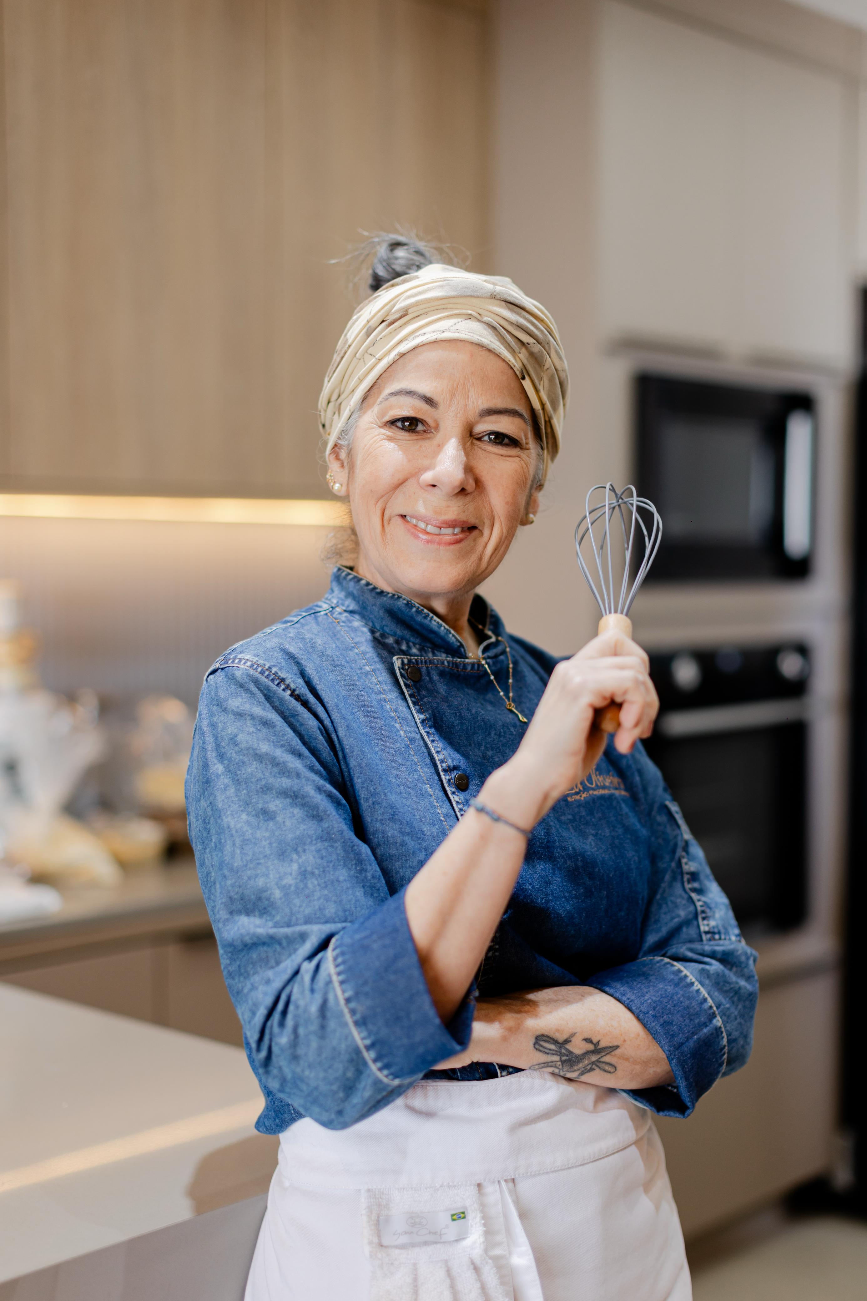 Lu Oliveira, nutricionista funcional, sorrindo com um fouet na mão
